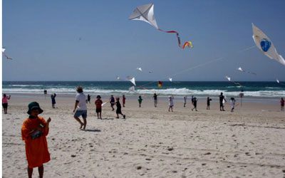 School children on the beach flying kites made in kite making workshop