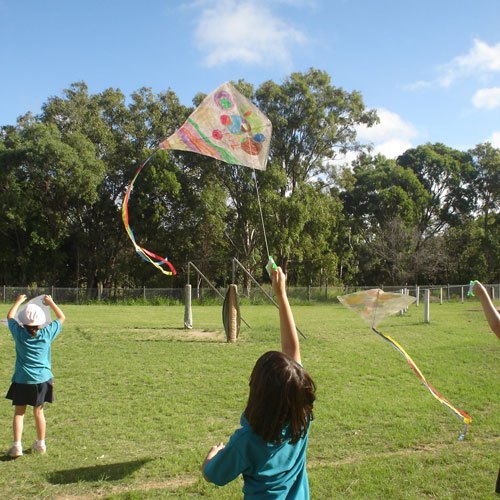 Boy launching the single string kite he made in class kite making workshop