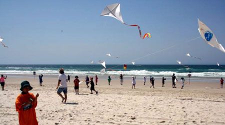 School children on the beach flying kites made in kite making workshop