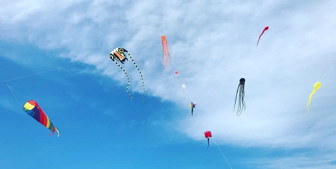 5 Inflatable octopus kites with spinsocks flying under them in a blue sky