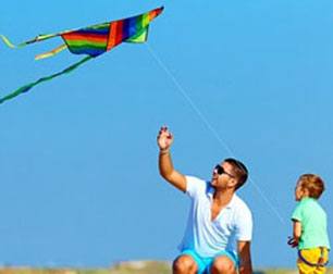 Dad and young son flying rainbow pattern delta kite