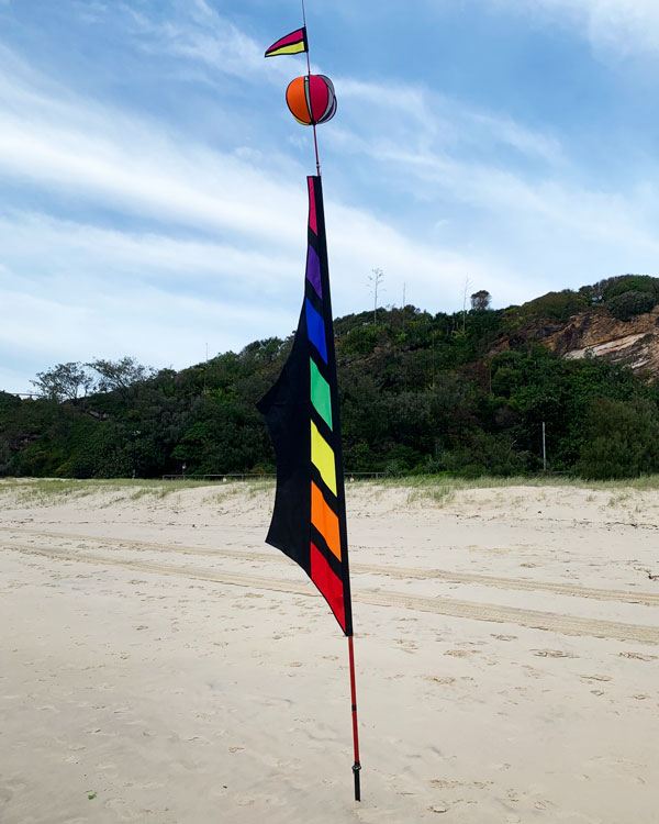 rainbow and black coloured banner on the beach
