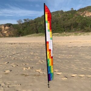 rainbow coloured feather on the sand