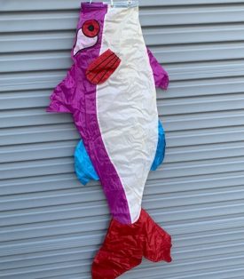 white and purple fish windsock against a wall